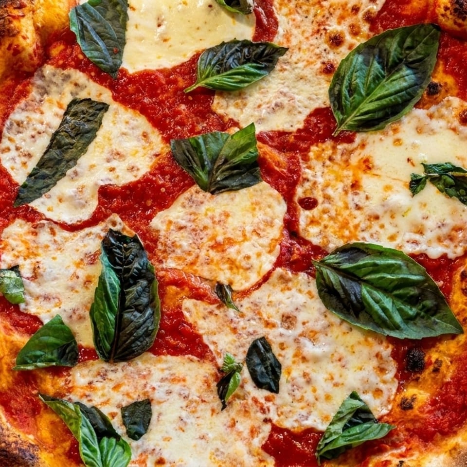 A close-up, top-down view of a freshly baked Margherita pizza with basil leaves.